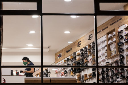 BELGRADE, SERBIA - OCTOBER 14, 2020: Employee of a shoe store footwear boutique standing alone around shoes wearing a respiratory face mask in Belgrade.のeditorial素材