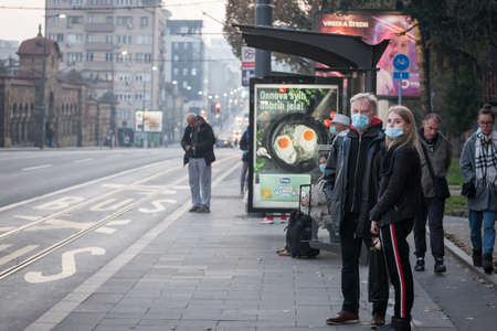 BELGRADE, SERBIA - NOVEMBER 8, 2020: Father and his daughter, waiting their bus at a stop in Belgrade wearing face mask protective equipmentのeditorial素材
