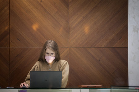 BELGRADE, SERBIA - OCTOBER 30, 2020: Woman staff worker, office employee, working on her laptop computer, alone, respecting social distancing wearing a face mask.のeditorial素材