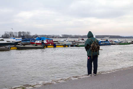 BELGRADE, SERBIA - FEBRUARY 28, 2020: Old man, Fisherman fishing on the Danube river during a rainy...