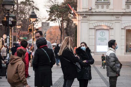 BELGRADE, SERBIA - DECEMBER 12, 2020: Young people, a girl, standing and queuing in a crowd, wearing...