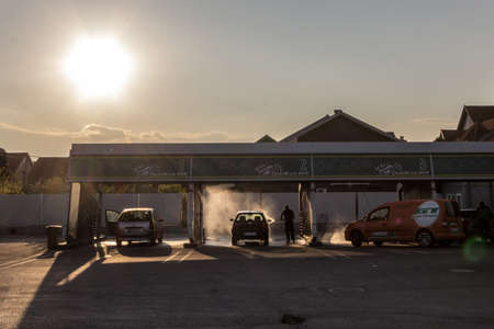 BELGRADE, SERBIA - APRIL 7, 2019: People washing their cars with high pressure water hoses in a car wash station of Belgrade, at dusk. Also called pranje auta, it is a symbol of transportation business. Picture of people washing cars and vehicles atdusk iのeditorial素材