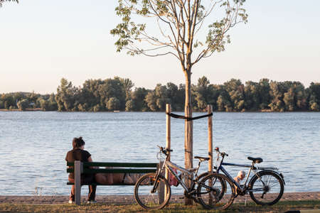 BELGRADE, SERBIA - MARCH 13, 2021: Three young men, serbs, belgradians, friends, sitting on a bench chatting, at the confluence between Sava and Danube rivers.のeditorial素材