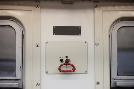 Handle of a train emergency brake system in a passenger car wagon with its iconic red lever used to trigger the braking of the carriage in case of accident.の写真素材
