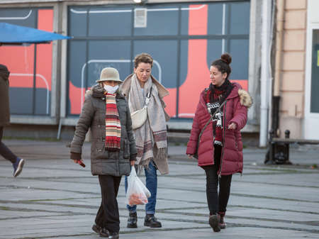 BELGRADE, SERBIA - FEBRUARY 21, 2021: Women, young girls and old woman, walking wearing face mask breathing protective equipment.のeditorial素材