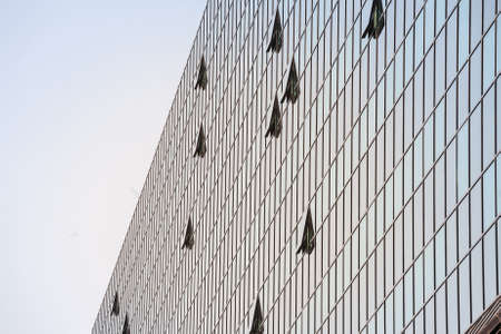abstract facade of a finance business building with mirror windows, some of them being opened to let...