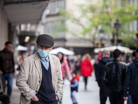 BELGRADE, SERBIA - MAY 3, 2021: Old senior man wearing a respiratory face mask standing on Kneza Mihaila street in Belgrade, in winter.のeditorial素材