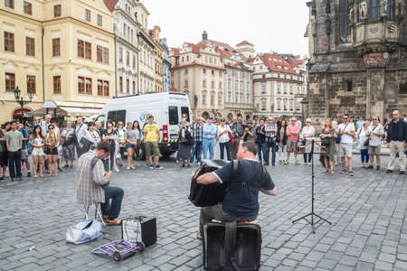 PRAGUE, CZECHIA - JULY 2, 2014: Selective blur on Accordionists playing accordion with crowd of tourists on Old Town Square (Staromestske Namesti) with Old Town Hall, a landmark, called staromestska radnice. Picture accordionists, street performersのeditorial素材