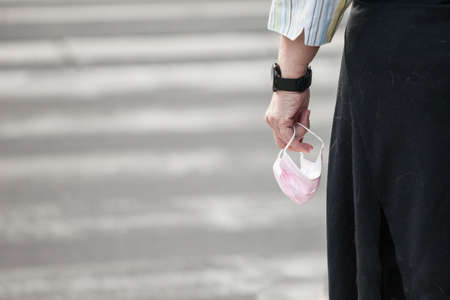 Selective blur and zoom on female hands holding a pink facemask respiratory protective equipment,...