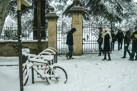 AIX EN PROVENCE, FRANCE - JANUARY 7, 2009: Pedestrians passing bicycles, bikes stranded under the snow in parc Rambot during an unusual snowstorm for the Aix southern climate.のeditorial素材