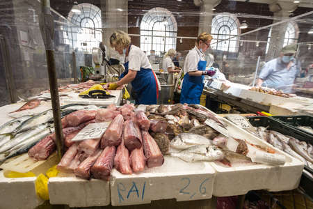 RIJEKA, CROATIA - JUNE 18, 2021: two women, workers, selling fish and seafood in ribarnica rijeka the covered indoor fish market, a monument of the city and a symbol of croatian fishing.のeditorial素材