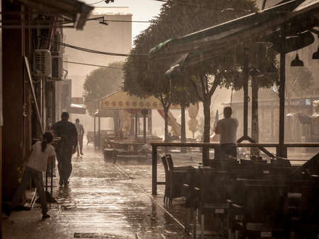 SMEDEREVSKA PALANKA, SERBIA - JULY 18, 2021: Selective blur on people running to find shelter to avoid a storm and heavy rains with floods in the main street of Palanka, Sumadija, Serbia.のeditorial素材