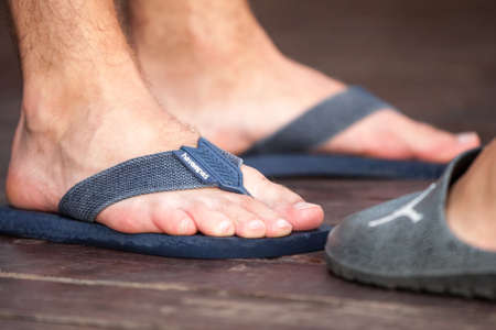BELGRADE, SERBIA - JULY 31, 2021: Selective blur on a male foot wearing flip flop sandals with the logo of Havaianas. Havaianas is a Brazilian designer and manufacturer of flip flop sandals.のeditorial素材