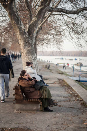 BELGRADE, SERBIA - JANUARY 27, 2017:  Selective blur on an old senior white woman sitting on a bench and using her smartphone to have a call and discuss with her telephone.のeditorial素材