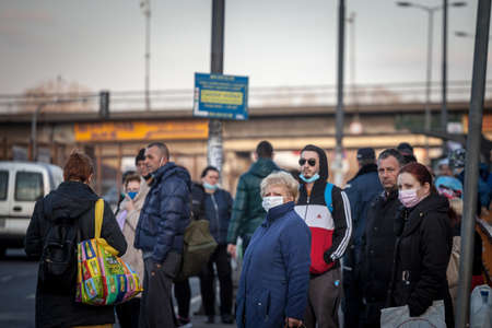 BELGRADE, SERBIA - FEBRUARY 28, 2021: Selective blur on a senior old woman in a Crowd of people waiting a bus at a stop in Belgrade wearing facemask on Coronavirus Covid 19 crisis.のeditorial素材