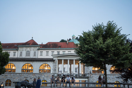 LJUBLJANA, SLOVENIA - JUNE 16, 2021: People, youngsters, sitting in the evening in front of columns of Ljubljana Central Market, or osrednja ljubljanska trznica, designed by Joze Plecnik, a landmark.のeditorial素材