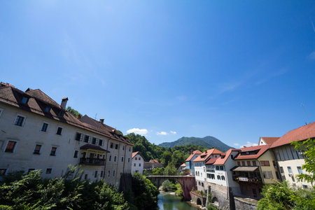 SKOFJA LOKA, SLOVENIA - JUNE 15, 2021: Panorama of the Selska sora river with the medieval bridge of Mamniti most, or capuchin bridge, in Skofja lka, a touristic destination of Slovenia.のeditorial素材