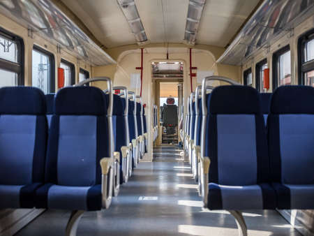 Row of Empty seats in a modern regional train with a driver cab in background, European style, on a travel in a countryside with a speed blur effect seen from the window.の写真素材