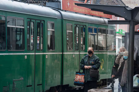 BELGRADE, SERBIA - APRIL 18, 2021: Senior old woman waiting at a tram stop for public transportation...