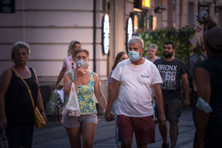 BELGRADE, AUGUST 16, 2021: Selective blur on Old senior man and woman, couple, wearing a facemask, waking in street of Belgrade in summer during  coronavirus covid 19 health crisis.のeditorial素材