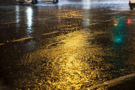 Selective blur on rain dripping with a speed blur movement on a wet road, with a flooded asphalt and...