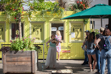 VILLACH, AUSTRIA - SEPTEMBER 13, 2021: Violonist playing music in front of People waiting at a Covid 19 open air testing facility to get PCR and antigen coronavirus testing, for the 3G regel rule to get covid pass.のeditorial素材
