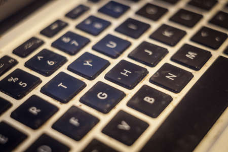 Selective blur on arrow keys of a laptop with an extremely dirty keyboard with black buttons needing some cleaning to prevent germs and diseases.の写真素材