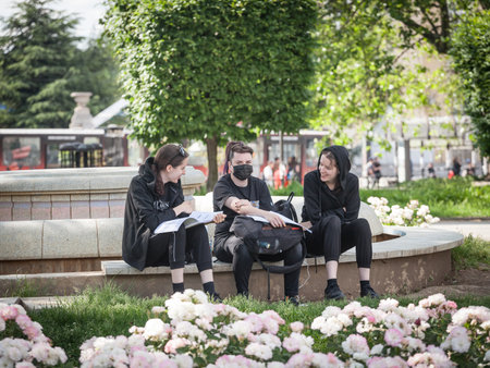 BELGRADE, MAY 20, 2021: Selective blur three young women, female girl students, studying outdoors in an exterior park, one wearing a facemask, during Covid 19 Coronavirus health crisis.のeditorial素材