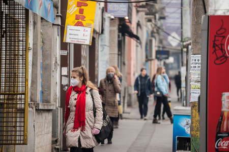 BELGRADE, SERBIA - NOVEMBER 15, 2021:  Selective blur on a young Woman, walking in the middle of a crowd wearing face mask respiration protective equipment on Coronavirus Covid 19 crisis.のeditorial素材