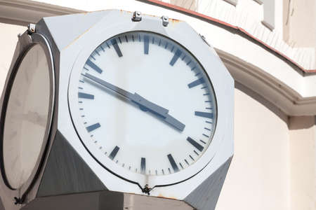 Close up on a public clock, with a vintage design from the 50s, indicating time, in the afternoon,...