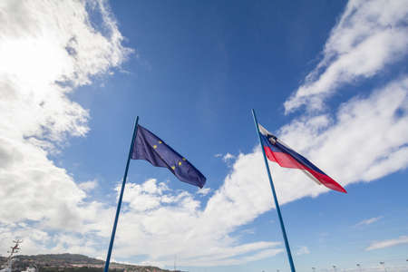 Flags of the European Union and Slovenia waiving together in the Slovenian city of Koper Slovenia is a member of the EU since 2004 and a major actor of the European game.の写真素材