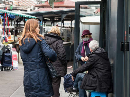 BELGRADE, SERBIA - NOVEMBER 11, 2021: Selective blur on an Old senior woman  wearing a respiratory face masks discussing in a group in a green market during the coronavirus covid 19 health crisis.のeditorial素材