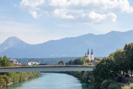Panorama of the suburbs of Villach with a selective blur on the steeple clocktower of pfarramt heiligenkreuz Kirche, or the Parish Church of heiligenkreuz, a catholic church of Villach, Austria, Carinthia.の写真素材
