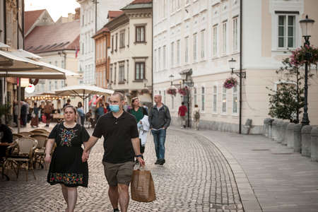 LJUBLJANA, SLOVENIA - JUNE 18, 2021: Selective blur on young man and woman, couple, one wearing a facemask the other not, waking  in street of Ljubljana during coronavirus covid 19  crisis.のeditorial素材