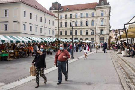 LJUBLJANA, SLOVENIA - SEPTEMBER 18, 2021: Selective blur on Old senior man and woman, couple, wearing a facemask, waking  in street of Ljubljana Central Market during coronavirus covid 19  crisis.のeditorial素材