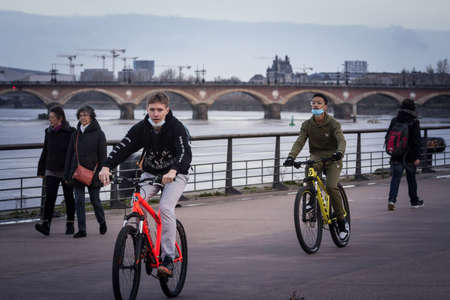 BORDEAUX, FRANCE - FEBRUARY 20, 2022: Selective blur on two young men, boys, biking with bicycles in...