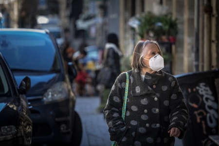 BORDEAUX, FRANCE - FEBRUARY 24, 2022: Old senior woman wearing a respiratory facemask walking in the streets in the city center of Bordeauxのeditorial素材