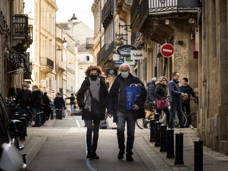 BORDEAUX, FRANCE - FEBRUARY 19 2022: Selective blur on Old senior man & woman, couple, with facemask, wlking in a street in Bordeaux with shopping groceries bags during coronavirus covid 19.のeditorial素材