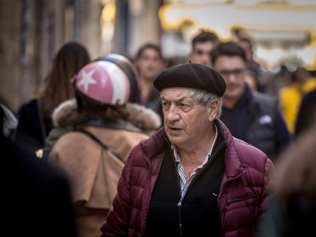 BORDEAUX, FRANCE - FEBRUARY 19 2022: Selective blur on a french old senior man wearing a beret walking in a crowded street of Bordeaux, one of the southwestern cities of France.のeditorial素材