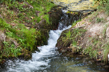 Streaming water, flowing through the rocks of a mountain alpine stream brook, with a speed blur on...