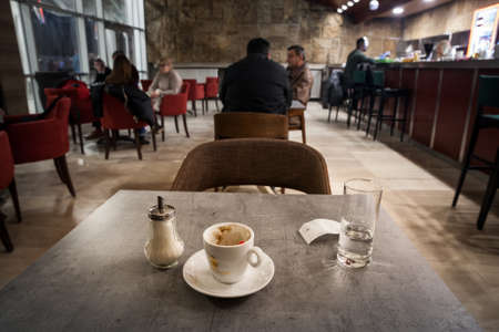 NOVI SAD, SERBIA - MARCH 20, 2022: Selective blur on an empty and dirty stained white porcelain coffee cup on display in the morning on the table of a cafe with a glass of water in the background.のeditorial素材