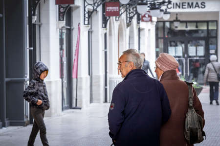 ARCACHON, FRANCE - FEBRUARY 22, 2022: Selective blur on an old couple, senior man and woman, married, walking, observing a younger kid, blurred, in the background.のeditorial素材