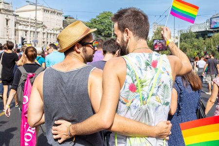 BELGRADE, SERBIA - SEPTEMBER 18, 2016: Two men hugging during the 2016 edition of the Belgrade Gay Pride (Beograd Prajd) holding rainbow flags. The parade happened this year without trouble, under huge police watch.のeditorial素材