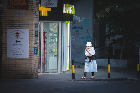 BELGRADE, SERBIA - JULY 22, 2022: Selective blur on Old woman walking in the streets of Belgrade wearing face mask protective equipment during Coronavirus Covid 19 crisis.のeditorial素材