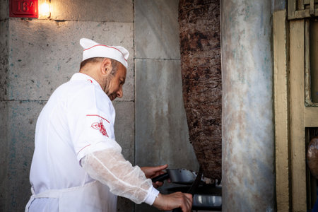ISTANBUL, TURKEY - MAY 21, 2022: Selective blur on a Turkish man, kebab master chef cutting a skewer of meat for a Doner kebab sandwich in Istanbul, Turkey.のeditorial素材