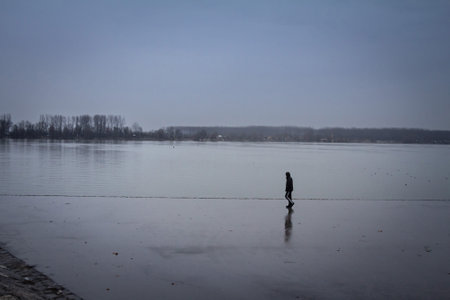 BELGRADE, SERBIA - JANUARY 31, 2016: man walking alone near the Danube river during a heavily foggy and rainy winter afternoon in Zemunon the quay of Zemunski kej.のeditorial素材