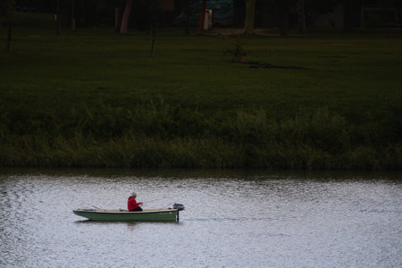 SZEGED, HUNGARY - SEPTEMBER 18, 2022: Old man, senior male relaxed and fishing on the Tisza river on...