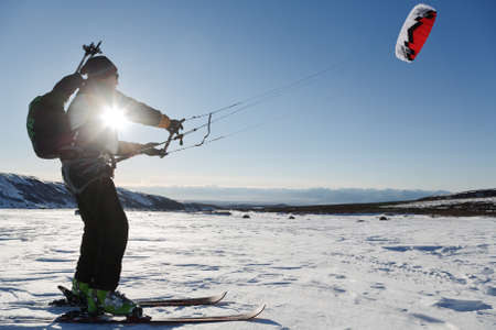 KAMCHATKA PENINSULA, RUSSIA - NOVEMBER 22, 2014: Snowkiting or kiteboarding - sportsman glides on skis on snow in sunny weather at sunset.のeditorial素材