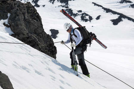 AVACHA VOLCANO, KAMCHATKA, RUSSIA - APRIL 21, 2012: Open Cup of Russia on ski-mountaineering on the Kamchatka Peninsula. Ski mountaineer rises on the rock on a rope with skis strapped to a backpack.のeditorial素材