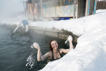 KAMCHATKA PENINSULA, RUSSIA - FEB 02, 2013: Smiling girl have a thermal bath in hot spring pool in the winter. Eurasia, Russian Far East, Kamchatsky Krai, Anavgay Village.のeditorial素材